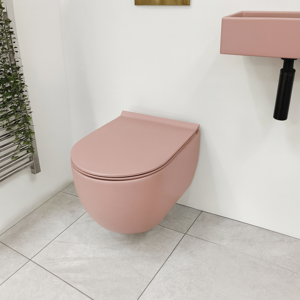 Lifestyle image of the Zero 3 Matt Pink Rimless Wall Hung Toilet & Soft Close Seat installed against a white wall